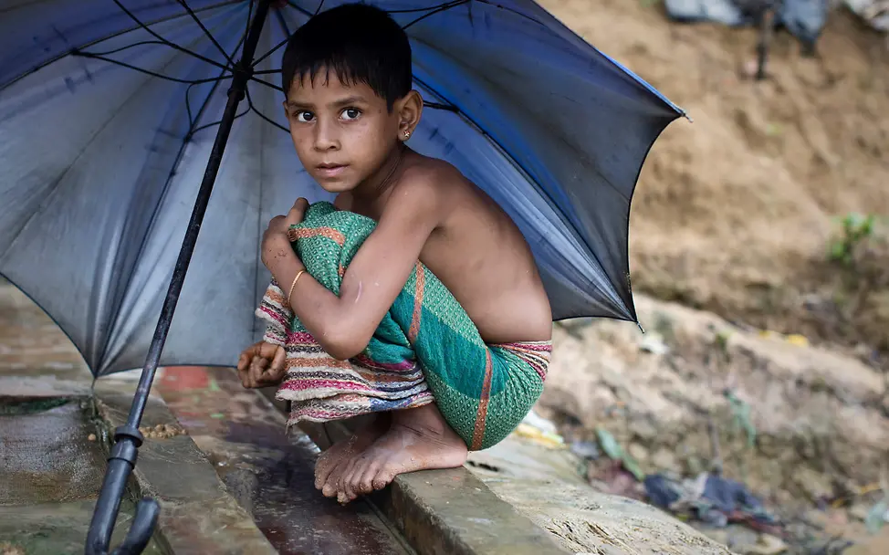 Rohingya-Mädchen sucht Schutz vor den Regenfällen | © UNICEF/Modola Monsun im Flüchtlingslager: Ein Rohingya-Mädchen sucht unter Regenschirm Schutz vor den Regenfällen