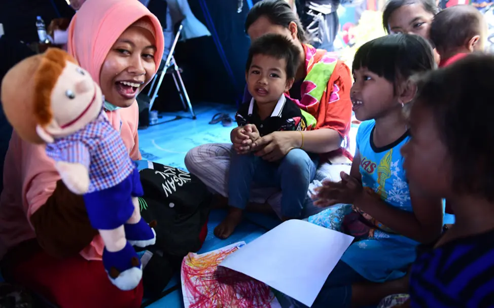 Eine Helferin zeigt in einem Kinderzentrum auf Sulawesi ein Puppenspiel | © UNICEF/Wilander Tsunami in Indonesien: Eine Helfern zeigt Kindern ein Puppenspiel