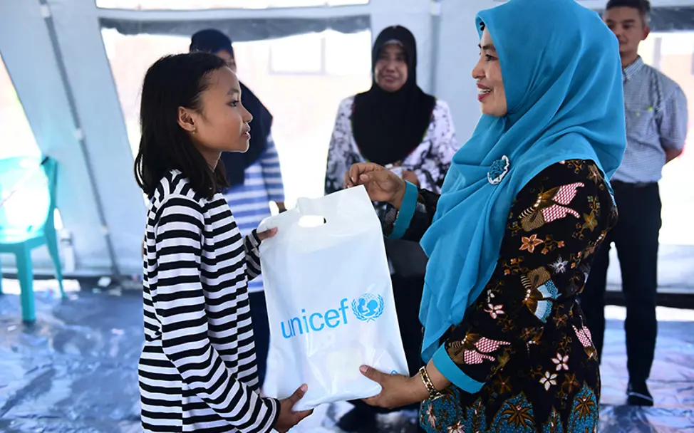 Sophia bekommt von der Direktorin ihre neuen Schulsachen. | © UNICEF/UN0251621/Wilander Sulawesi: Sophia bekommt von der Direktorin ihre neuen Schulsachen.