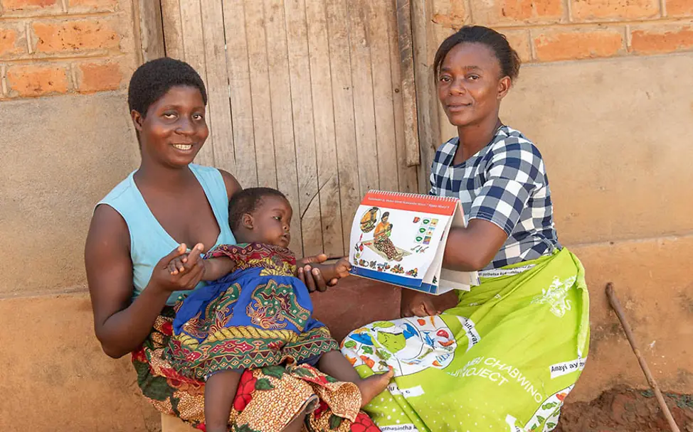 Ganizani berät Mütter zu gesunder Ernährung. | © UNICEF Malawi: Ganizani erklärt Elizabeth und ihrer Tochter, wie sie sich ausgewogen ernähren können.