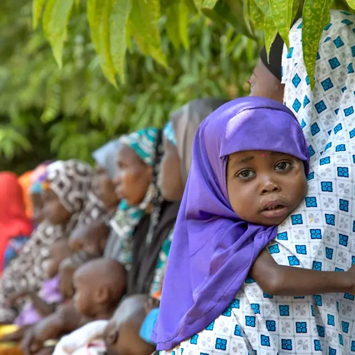 Mangelernährung in Nigeria: Kinder leiden Hunger und brauchen dringend Essen, um zu überleben. | © UNICEF/Esiebo Ein unterernährtes 2-jähriges Mädchen mit lila Kopftuch klammert sich an seine Mutter.
