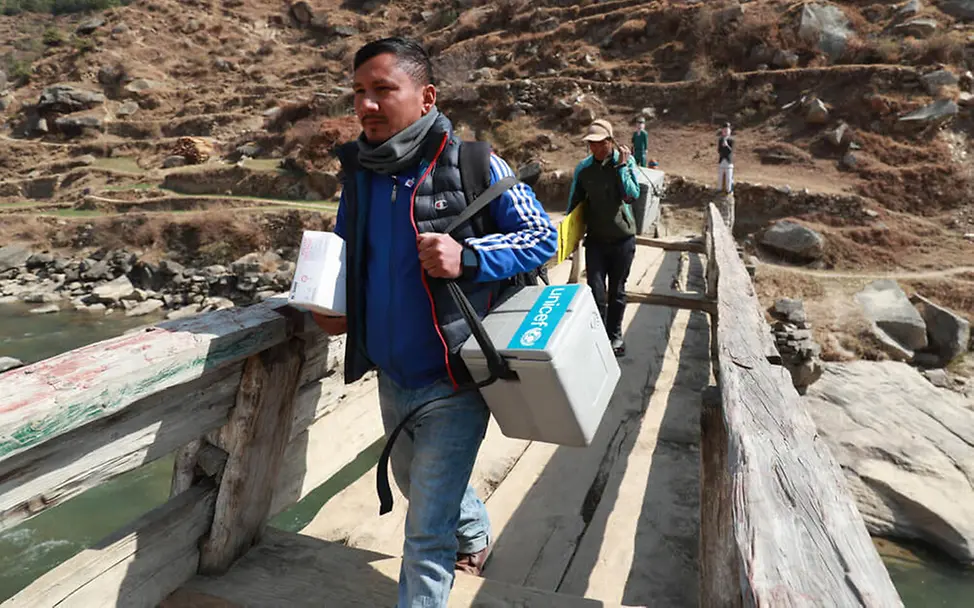 COVAX: In Nepal trägt ein humanitärer Helfer eine Kühltasche mit Corona-Impfstoffdosen. | © UNICEF Corona-Impfungen: UNICEF stellt für die COVAX-Initiative Ausrüstung wie Kühlboxen bereit. Jetzt spenden!