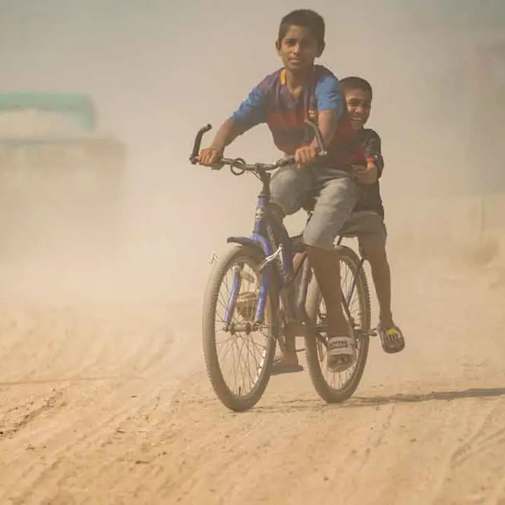 Kinder spielen auf einem Fahrrad auf einer stark verschmutzten Straße in Bangladesch I © UNICEF/Haque Lungenentzündung verursacht durch Luftverschmutzung in Bangladesch