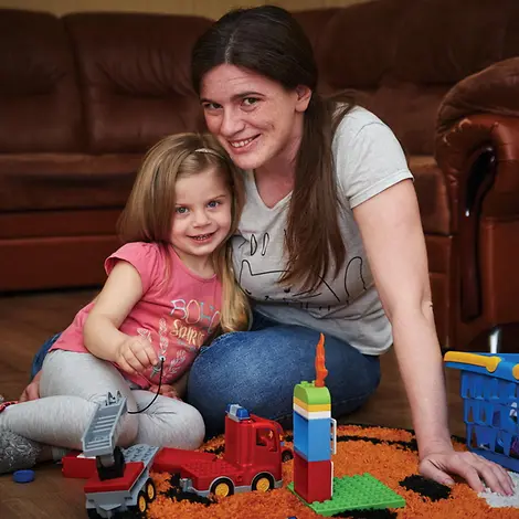 Mama und Tochter spielen zusammen mit Lego und Feuerwehrauto. | © UNICEF/Zmey Eine Mutter und ihre Tochter spielen zuhause.