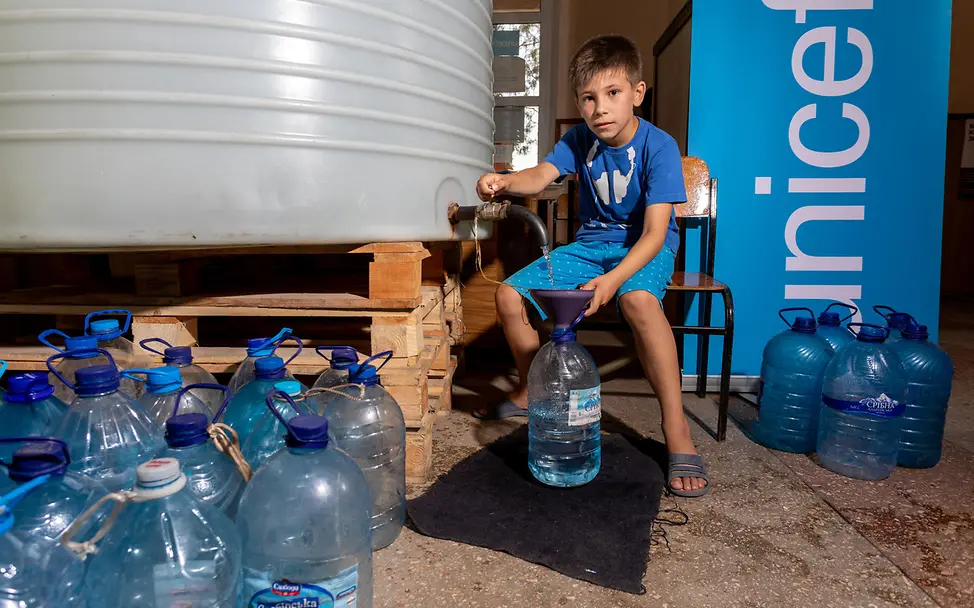 David hilft beim Abfüllen von Wasser. | © UNICEF/Filippov Ukraine-Krieg Verlauf: David, acht Jahre alt, hilft beim Abfüllen von 5-Liter-Plastikflaschen.