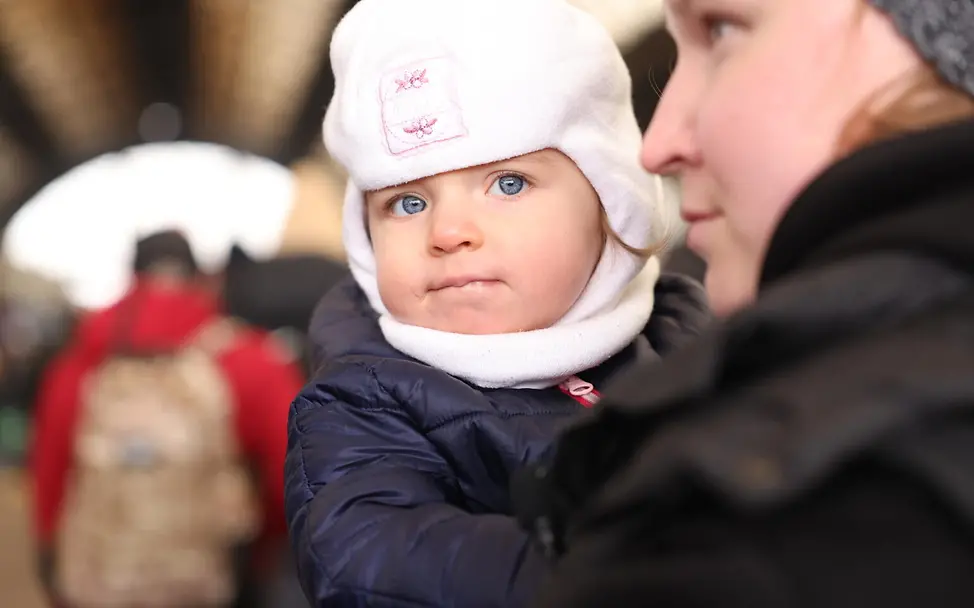 Am 27. Februar wartet Asya mit einem Kleinkind auf einem Bahnhof im Westen der Ukraine auf einen Evakuierungszug. | © UNICEF/Moskaliuk Ukraine-Krieg Verlauf: Am 27.2. wartet Asya mit einem Kleinkind auf dem Bahnhof im Westen der Ukraine.