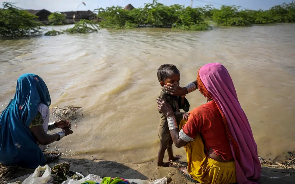 Pakistan_ Überschwemmungen | © UNICEF/UN0698975/Zaid Pakistan: Mutter wäscht Kind in Flutwasser.