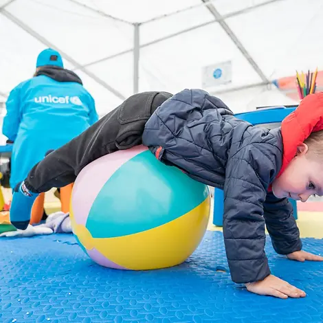 UNICEF | Hilfe für Kinder in der Ukraine | © UNICEF/Holerga UNICEF | Hilfe für Kinder in der Ukraine: Ein kleiner Junge rollt über einen Ball in einer "Blue Dot"-Anlaufstelle in Rumänien.