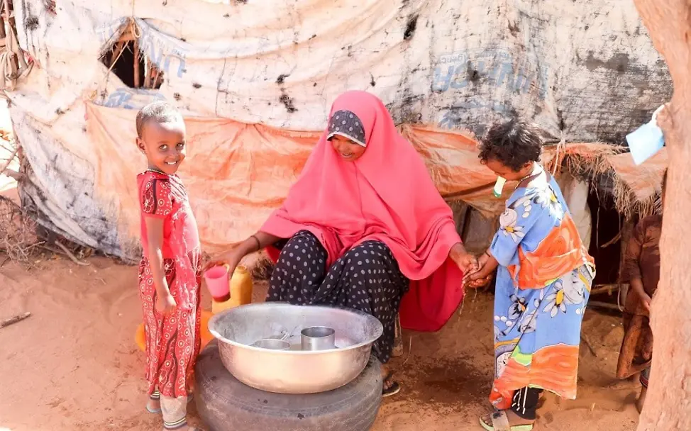 Klimawandel: So sprechen Sie mit Kindern darüber. | © UNICEF/Taxta Somalia: Eine Frau mit zwei Kindern vor einer Schüssel mit Wasser.
