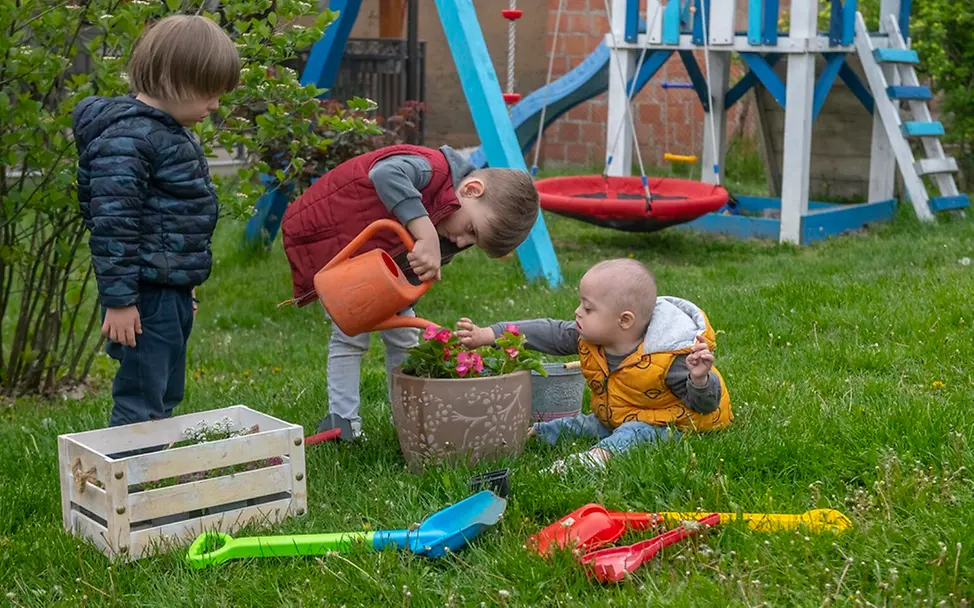Klimawandel: So sprechen Sie mit Kindern darüber | © UNICEF/Pancic Serbien: Drei Kinder spielen im Garten und gießen eine Blume mit einer Gießkanne.