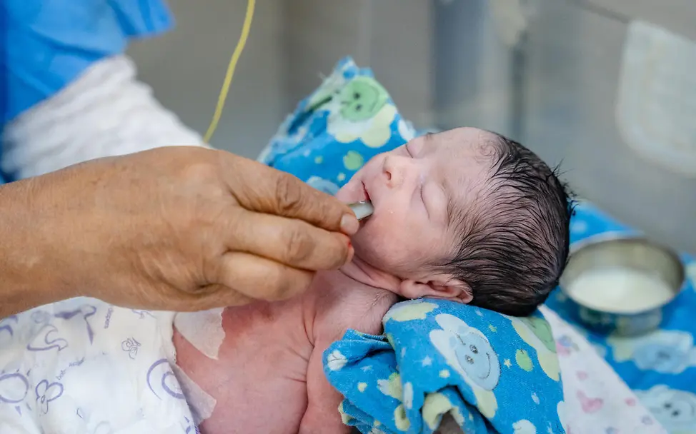Krankenpflegehelferin füttert ein Neugeborenes auf Intensivstation in Kathmandu. © UNICEF/UN0687321/Upadhayay UN0687321
