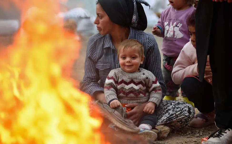 Eine Mutter und ihr Baby wärmen sich an einem Feuer in einer Notunterkunft. | © UNICEF/Ölçer Spenden Türkei: Eine Mutter sitzt mit ihrem Baby kurz nach dem Erdbeben an einem wärmenden Feuer in einer Notunterkunft.