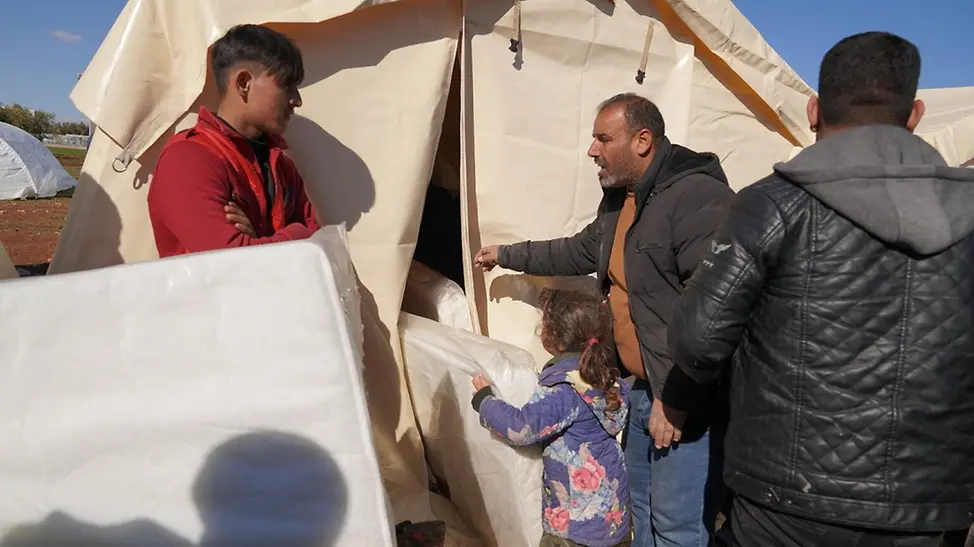 Erdbeben in Syrien: So hilft UNICEF | © UNICEF/OCHA Erdbeben in Syrien: Familien tragen Hilfsgüter wie Matratzen in ihr behelfsmäßiges Zelt.