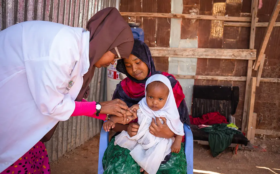 Wir erklären den Müttern, wie wichtig eine Masernimpfung ist. | © UNICEF/Ekpu VII Photo Muniish Cadan Ismail sitzt auf dem Schoß ihrer Mutter und wird gegen Masern geimpft.