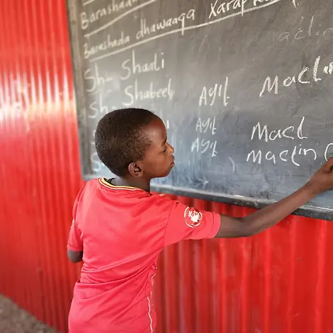 Dürre in Somalia: Adan will weiterlernen I UNICEF Somalia/Mumin Adan schreibt an die Tafel des Lernzentrums im Binnenvertriebenenlager in Deebwin, Somalia.