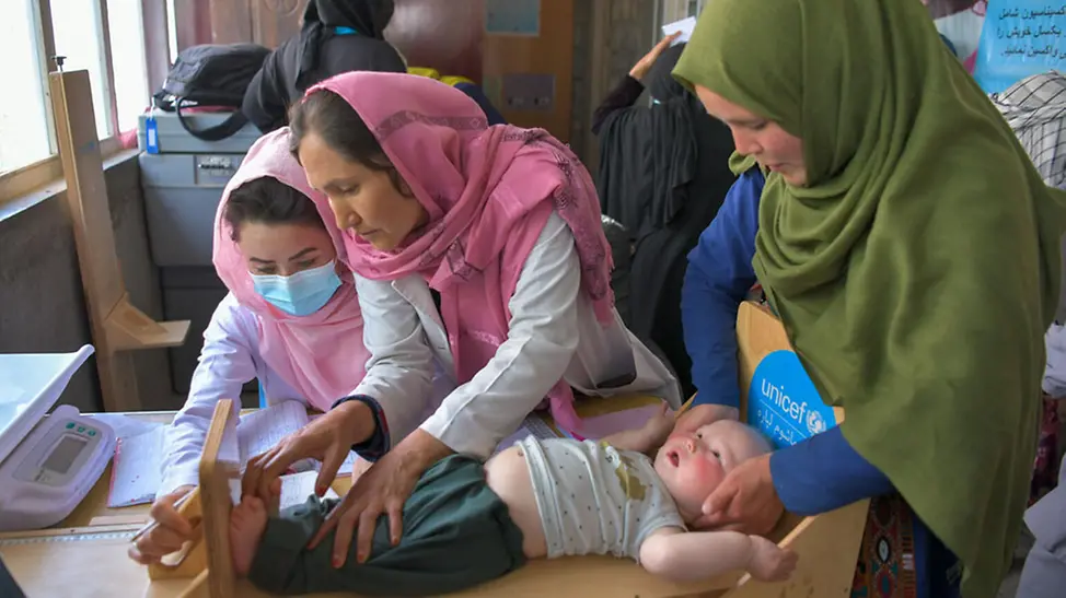 Afghanistan: Ernährungsspezialistinnen untersuchen ein Kind auf Mangelernährung | © UNICEF/Karimi Afghanistan: Ernährungsspezialistinnen untersuchen ein Kind auf Mangelernährung