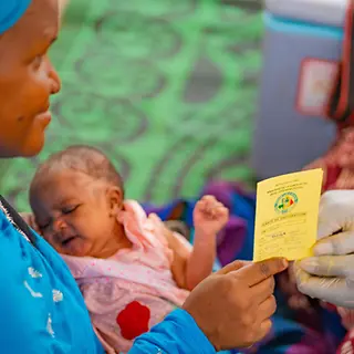 Malaria Impfung: Eine Mutter in Mali mit ihrem Baby auf dem Schoß bekommt ihren Impfausweis. 