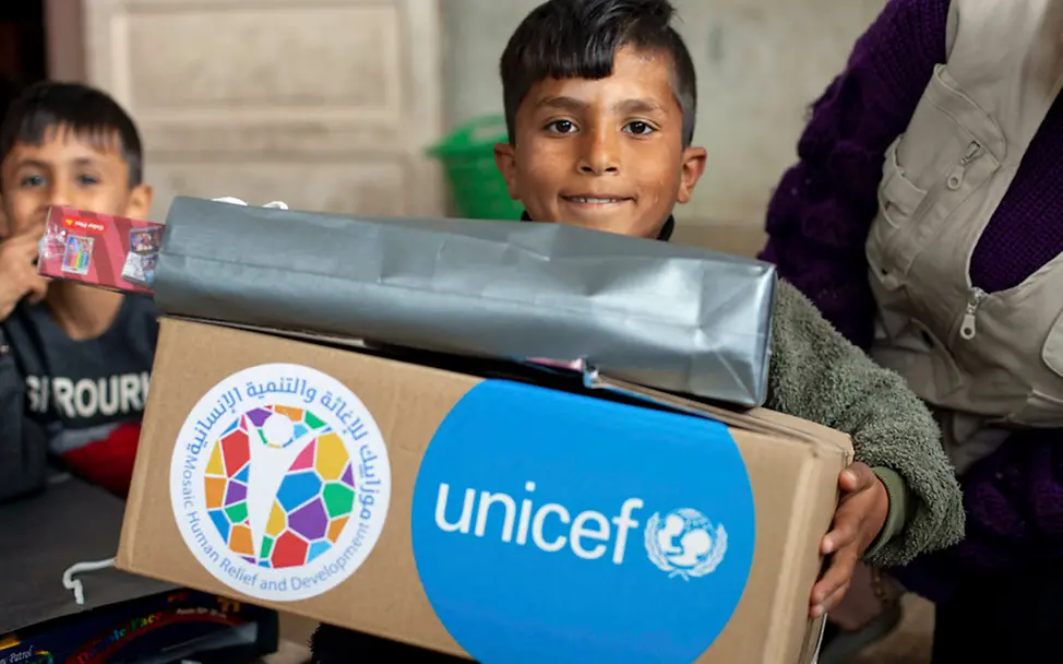Ein Junge bekommt einen UNICEF-Karton mit Hilfsgütern, z.B. mit Kleidung | © UNICEF/Issa Erdbeben Syrien Türkei: Ein Junge bekommt einen Karton mit UNICEF-Hilfsgütern