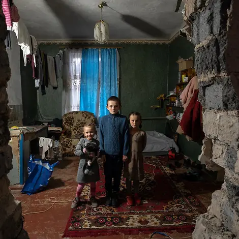 Ukraine: Kinder sind zuhause nicht sicher |© UNICEF/Filippov Jahrestag Ukraine-Krieg: Ukrainische Kinder stehen in ihrem zerstörten Haus.