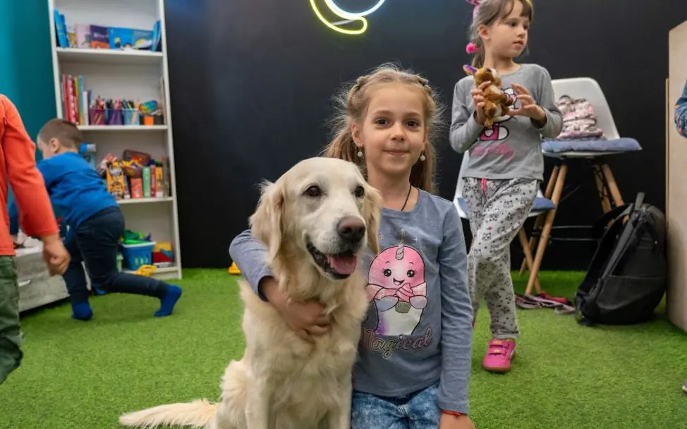 Ukraine: Hunde-Therapie in einem UNICEF Spilno © UNICEF/Filippov Jahrestag Ukraine-Krieg: Mädchen sitzt mit Therapiehund in einem UNICEF Spilno Child Spot.