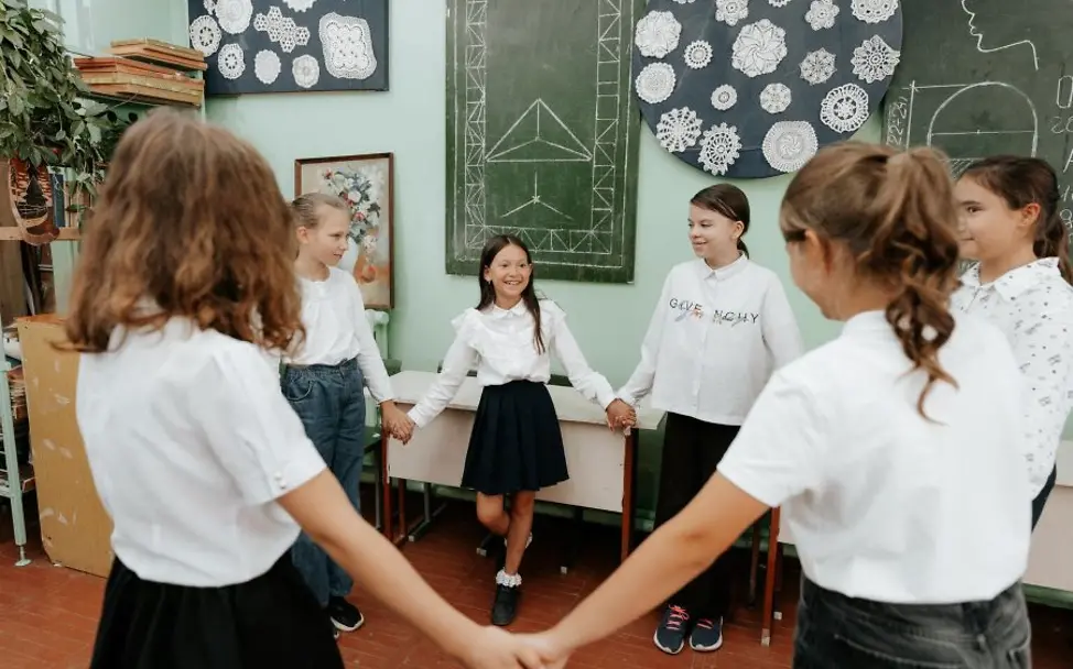 Moldau: Ukrainische geflüchtete Kinder gehen zur Schule |© UNICEF/Dogoter Jahrestag Ukraine-Krieg: Mädchen in Schuluniform stehen im Kreis und halten Hände.