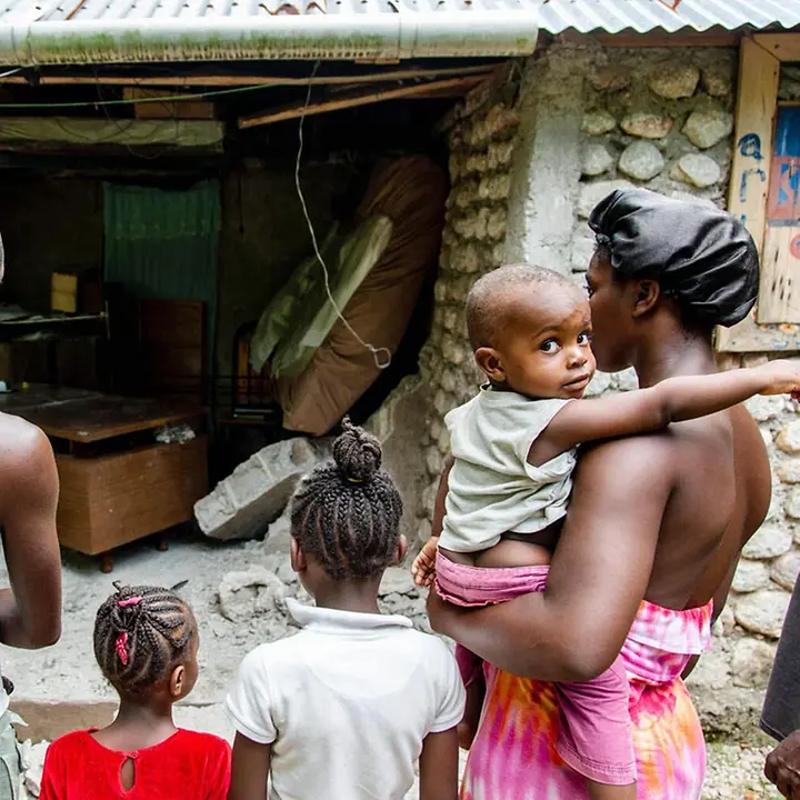 Eine Familie in Haiti steht vor ihrem zerstörten Zuhause | © UNICEF/Rouzier Haiti Erdbeben Nothilfe: Nach dem schweren Erdbeben 2021 steht eine Familie vor ihrem zerstörten Zuhause