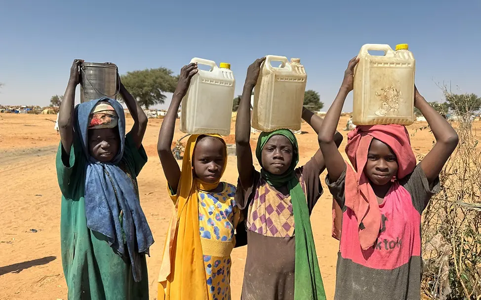Sudan: So viele Kinder wie nie zuvor benötigen lebensrettende Hilfe | UNICEF/Le Du Wasserknappheit in der Krise: Eine Gruppe von Kindern in einem Flüchtlingscamp im Tschad trägt Wassereimer.