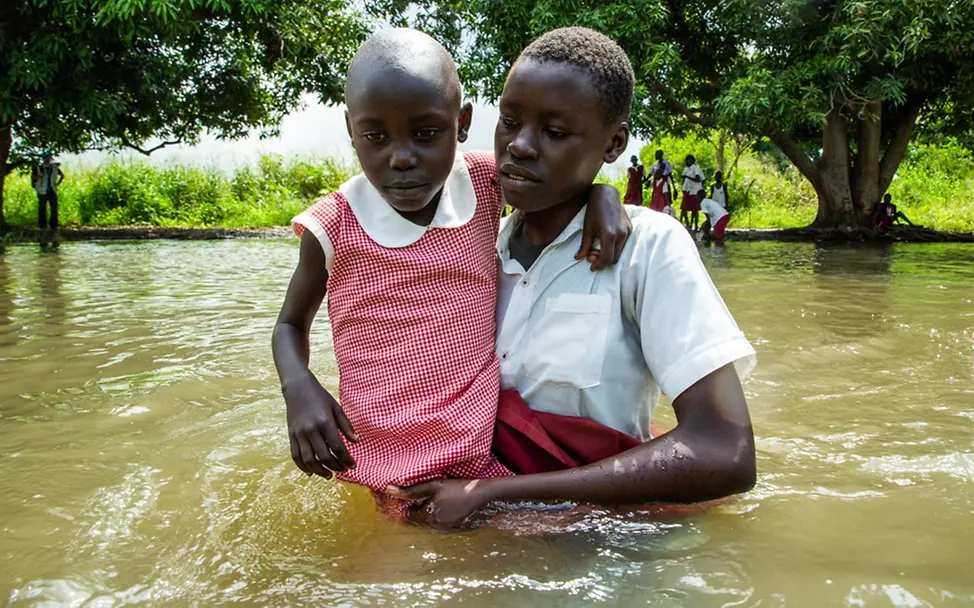 Südsudan: Eine ältere Schülerin trägt ein jüngeres Mädchen durch das Hochwasser