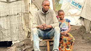 Gentille, 8 Jahre, und ihr Vater Manu vor ihrer Unterkunft in der Kizimba-Stätte für Vertriebene in Sake, in der Provinz Nord-Kivu in der DR Kongo | © UNICEF/UNI510509/Ushindi Gentille, 8 Jahre, und ihr Vater Manu vor ihrer Unterkunft in der Kizimba-Stätte für Vertriebene in der DR Kongo