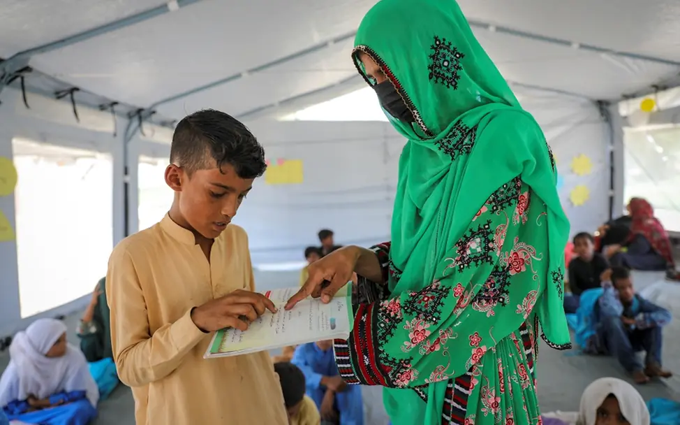 Pakistan 2022: Daniyal lernt mit seiner Lehrerin Fazia und seinen neuen Schulbüchern. | © UNICEF/UN0701857/Zaidi Pakistan 2022: Daniyal lernt mit seiner Lehrerin Fazia und seinen neuen Schulbüchern.