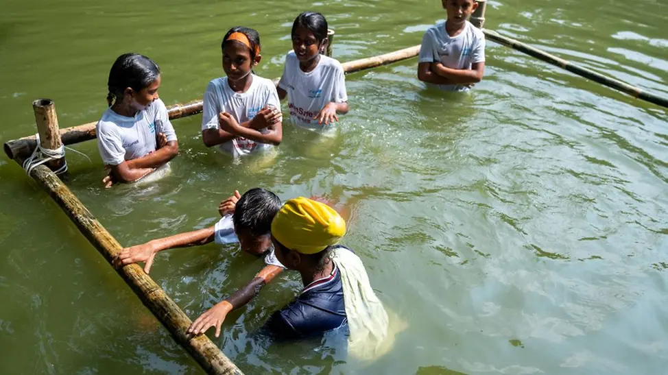 In einem geschützten Bereich zeigt Mim den Kindern erste Schwimmübungen.
