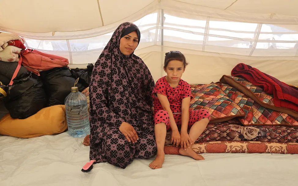 Eine Mutter mit ihrer Tochter sitzt auf dem Boden eines Zeltes