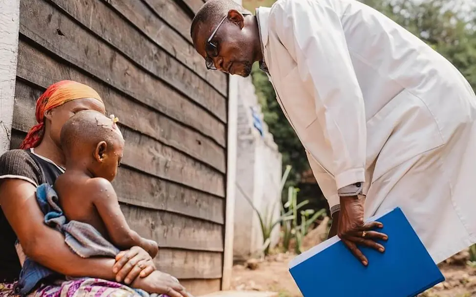 Mpox Virus: Ein Arzt im Gespräch mit einem jungen Mpox-Patienten und seiner Mutter im Kongo | © UNICEF/Benekire Mpox Virus: Ein Arzt im Gespräch mit einem jungen Mpox-Patienten und seiner Mutter im Kongo