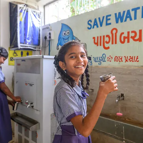Ein Mädchen trink Wasser aus einem Becher