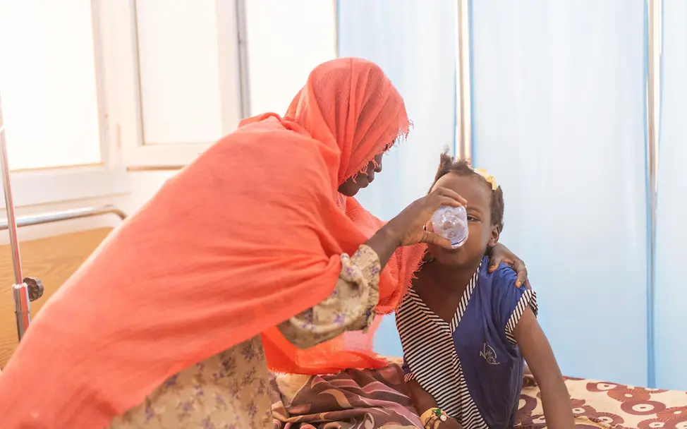 Eine Mutter gibt ihrer 8-jährigen Tochter etwas zu trinken