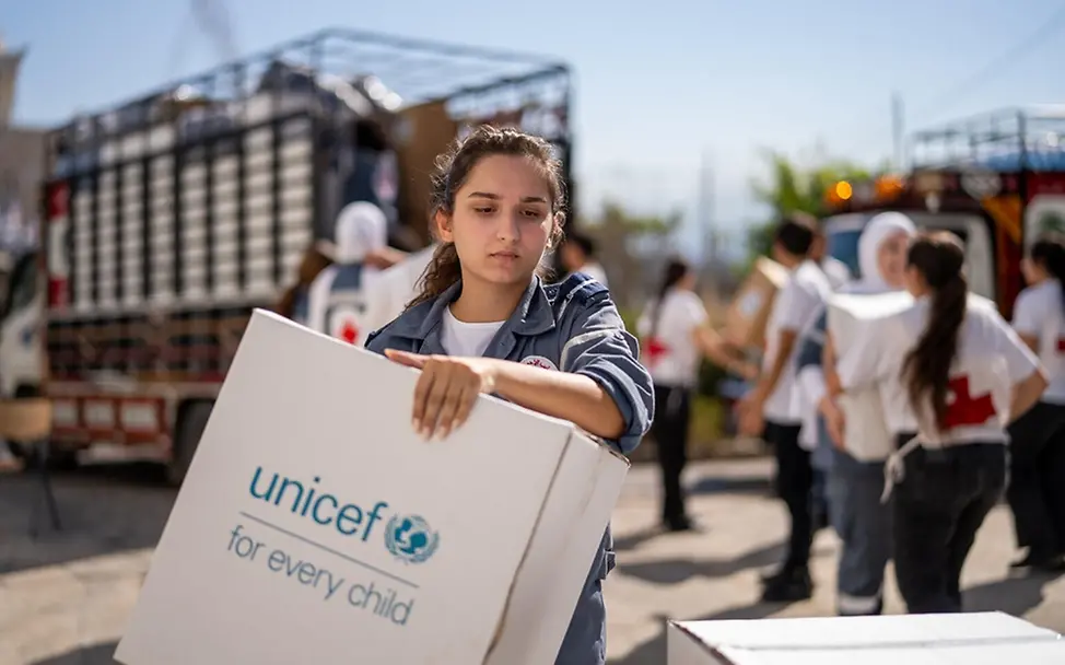 Libanon Kinder: Eine Helferin vom libanesischen Roten Kreuz trägt eine Box mit UNICEF-Hilfsgütern | © UNICEF/Choufany Libanon Kinder: Eine Helferin vom libanesischen Roten Kreuz trägt eine Box mit UNICEF-Hilfsgütern
