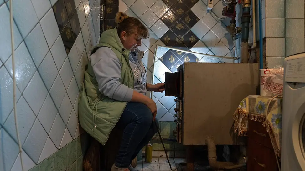 Eine Frau feuert einen Heizkessel an | © UNICEF/Filippov Ukraine Winter Nothilfe: Eine Frau feuert einen Heizkessel an mit Briketts, die sie von UNICEF bekommen hat