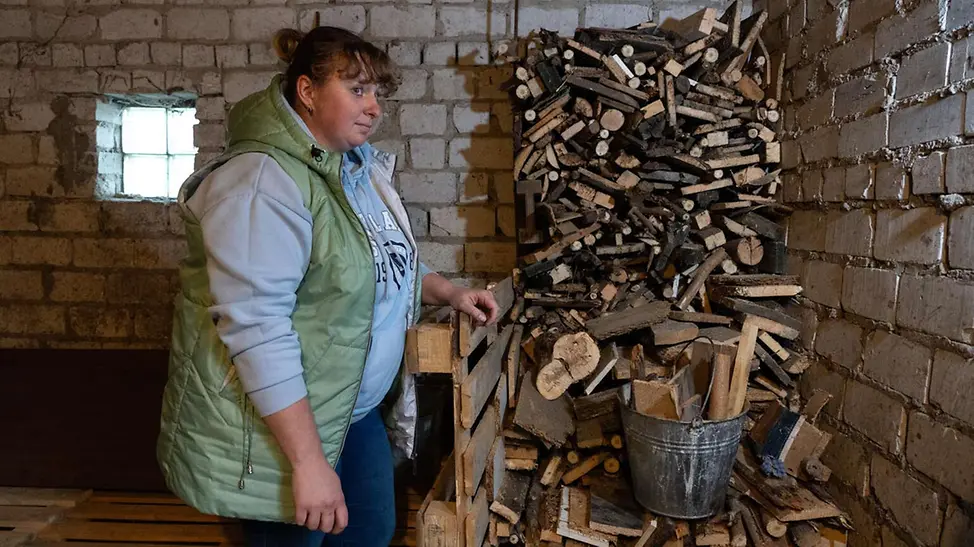 Eine Mutter in der Ukraine steht vor einem Stapel Brennholz für den Winter | © UNICEF/Filippov Ukraine Winter Hilfe: Eine geflüchtete Mutter in der Ukraine steht vor einem Stapel Brennholz für den Winter