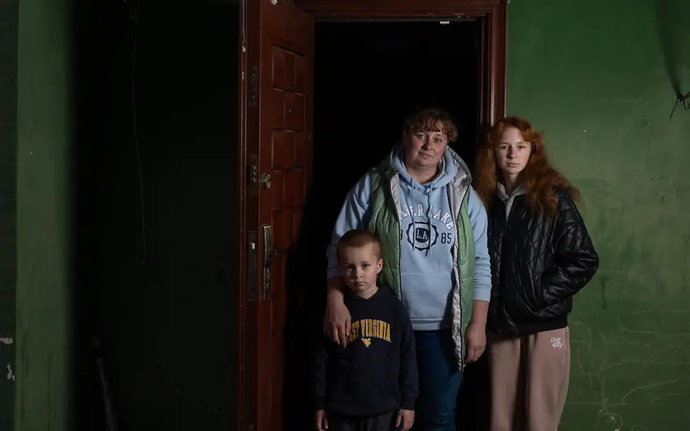 Eine Mutter steht mit ihren beiden Kindern in der Ukraine einem kleinen Gartenhäuschen | © UNICEF/Filippov Ukraine Winter Hilfe: Diese Familie verbringt den Kriegswinter nach der Flucht in einem kleinen Gartenhäuschen