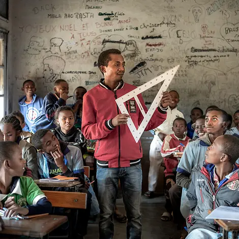 Schulunterricht in Madagaskar | © UNICEF/UNI658286/Andrianantenaina Ein Lehrer mit einem großen Geodreieck wird von seinen Schülern betrachtet