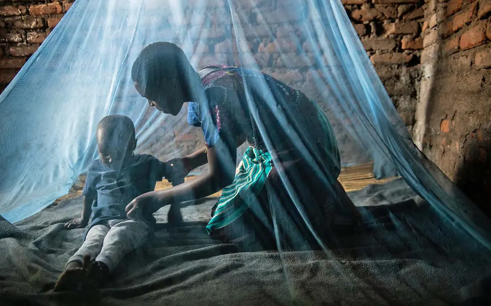 Malaria Kinder schützen: Eine Mutter mit ihrem Sohn unter einem Moskitonetz 