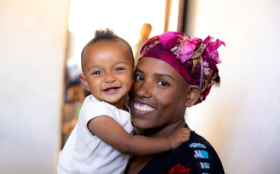 Ein lächelndes gesundes Baby auf dem Arm seiner Mutter in Äthiopien. | © UNICEF/Pouget Impfungen Baby: Ein lächelndes gesundes Baby auf dem Arm seiner Mutter in Äthiopien.