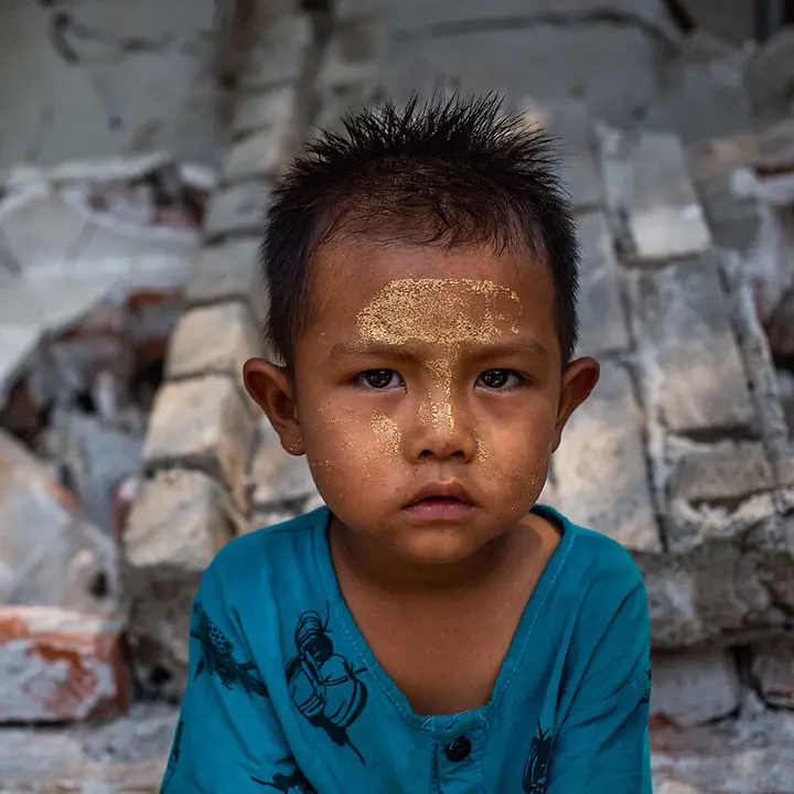 Ein Junge sitzt nach dem schweren Erdbeben vor einer zusammengestürzten Wand | © UNICEF/Htet Erdbeben Myanmar spenden: Ein Junge sitzt nach dem schweren Erdbeben vor den Trümmern von Gebäuden