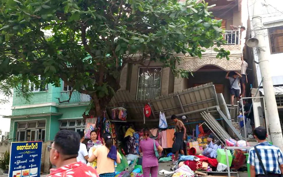 Menschen versammeln sich vor einem zerstörten Gebäude