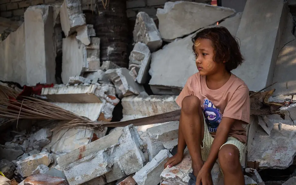 Ein Mädchen in Myanmar in den Trümmern eines Hauses