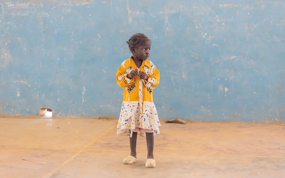 Die vierjährige Walaa | © UNICEF/UNI681039/Elfatih Ein kleines Mädchen steht vor einer blauen Wand