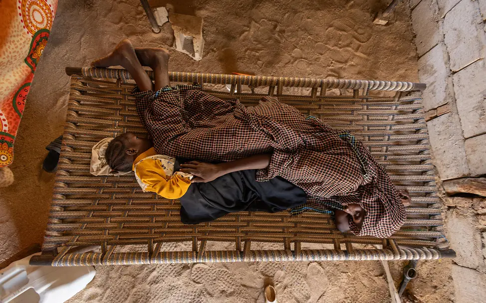 Mutter und Tochter schlafen eng beieinander | © UNICEF/UNI681100/Elfatih Eine Mutter und ihr Kind auf einem Bett