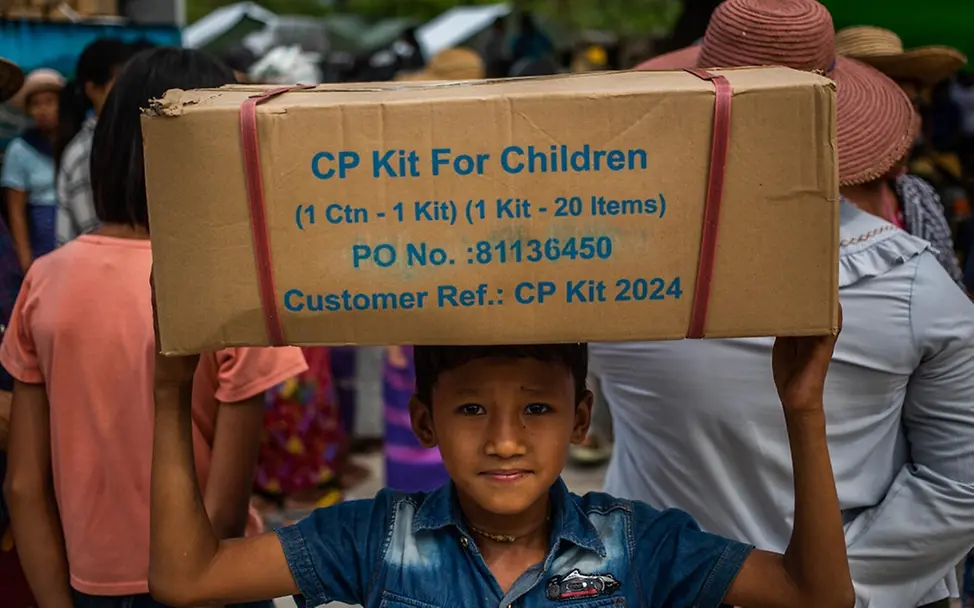 Ein Junge hält stolz ein Paket mit Hilfsgütern für Kinder in der Hand. | © UNICEF/Htet Hilfe für Myanmar: CP Kit For Childdren.