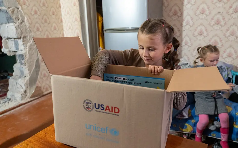 UNICEF/Filippov | UNICEF verteilt Winterkleidung an Kinder und Familien Ukraine: Ein Mädchen packt Kleidung aus einem Karton aus