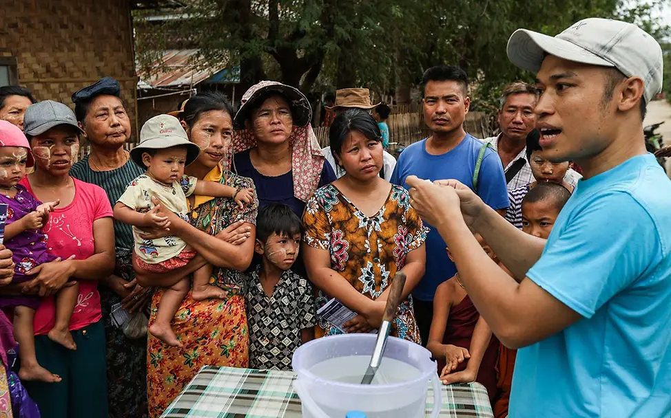 Erdbebenopfer in Myanmar hören zu, wie ein UNICEF-Helfer ihnen Wasserreinigungstabletten erklärt | © UNICEF/Maung Nyan Erdbeben Myanmar spenden: Ein UNICEF-Helfer erklärt Menschen die Nutzung von Wasserreinigungstabletten.